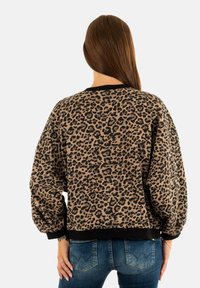 Pullover in stampa leopardata beige e nera, con scollatura rotonda e polsini a costine, realizzato in morbido tessuto testurizzato.