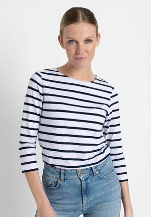 Langärmliges gestreiftes Oberteil in Weiß mit Navy-Streifen, runder Ausschnitt und weichem Baumwollstoff, kombiniert mit hellblauen Jeans.