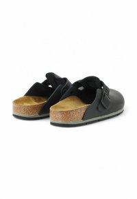 Scarpe slip-on nere con suola in sughero, caratterizzate da una superficie esterna liscia e una tracolla posteriore per supporto. La suola è in gomma per una migliore aderenza.