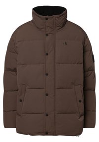 Brun pufferjacka med hög krage, tryckknappsstängning, sidofickor och en subtil logotyp på bröstet. Slät, quiltad textur.