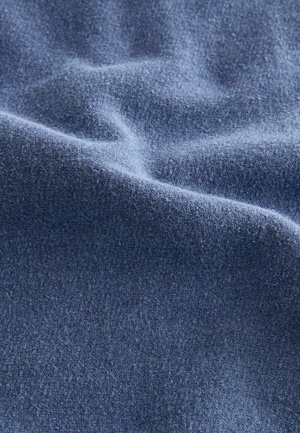 Texture, minkštas audinys giliu mėlynu atspalviu, demonstruoja lygu paviršių su subtiliais variacijomis ir raukšlėmis. Medžiaga atrodo šilta ir jauki.