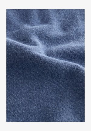 Teksturowana, miękka tkanina w głębokim odcieniu niebieskiego, ukazująca gładką powierzchnię z delikatnymi różnicami i fałdami. Materiał wydaje się ciepły i przytulny.