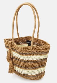 Sac en paille tissée avec un motif rayé en marron, crème et beige. Comprend deux longues anses et un pompon décoratif. Étiquette visible à l'intérieur.