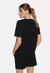 Sort bomulds-t-shirt med korte ærmer og en afslappet pasform, parret med matchende sorte shorts. Enkel design, rene linjer, ingen mønstre.