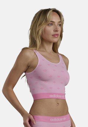 Rosa geripptes Crop-Top mit einem dezenten Logo-Muster und einem kontrastierenden rosa Band mit "adidas"-Branding am unteren Rand.