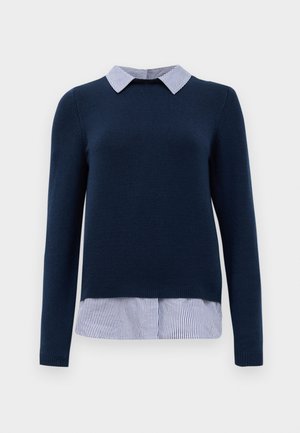 Pull en bleu marine à manches longues avec une chemise à col rayée qui dépasse en bas, présentant une texture lisse et un design ajusté.