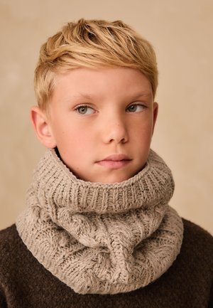 Beige strikket halsrør med tekstureret kabelmønster og ribbet øverste kant, båret over en mørk sweater. Glat overflade, hyggeligt udseende.