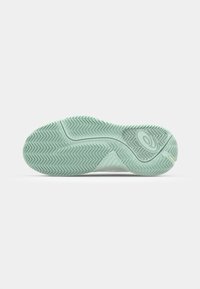 Semelle de chaussure en caoutchouc vert clair avec un motif de traction en zigzag, présentant un design incurvé et un détail de logo près du talon.