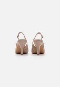 Beige mokka slingback-kengät pyöreällä kärjellä, hoikalla stiletto-korkealla ja säädettävällä nilkkahihnalla. Pehmeä tekstuuri ja minimalistinen muotoilu.
