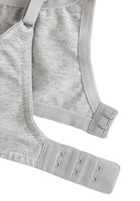 Šedá měkká tkaninová podprsenka bez výztuže s nastavitelnými ramínky, vybavená zapínáním na háček a očko a cik-cakovým prošitím na okrajích.