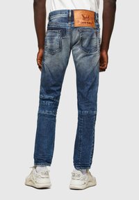 Blå denimjeans med en blekt tvätt, rak passform, dubbla bakfickor och en brun läderlogga på midjan.