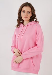 Felpa con cappuccio rosa, dal taglio oversize, con tasca anteriore, polsini a coste e cordoncini. Tessuto morbido con una superficie liscia.