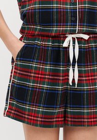 Plaid shorts with a red, green, blue, and yellow pattern. Features an elastic waistband, drawstring, and side pockets. Cotton blend material.