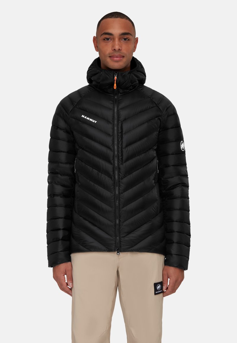 Zwarte pufferjack met een chevronpatroon, hoge kraag, rits aan de voorkant en oranje trekker. Bevat het merkteken op de borst en de mouw.