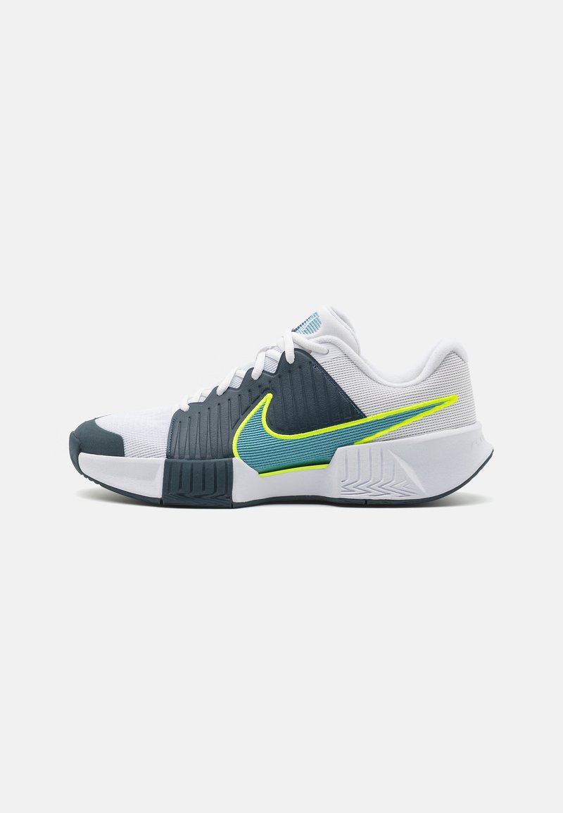 Sapatilha desportiva Nike com um cabedal branco e azul marinho, com detalhes texturizados, swoosh verde neon e uma sola padrão para tração.