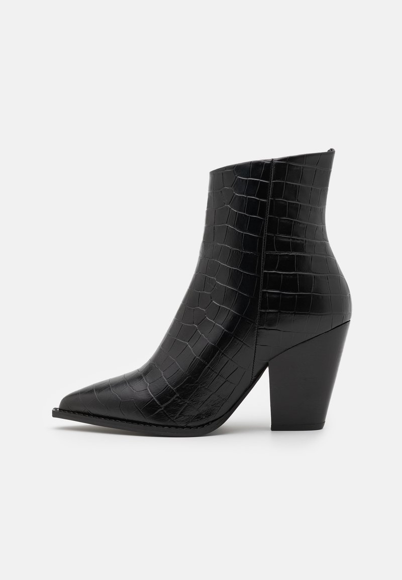 Botte de cheville noire avec un bout pointu, en cuir verni embossé crocodile, présentant un talon épais et une texture lisse et brillante.