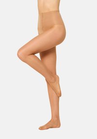 Nøgnefarvede strømpebukser med høj talje, sømløst design, gennemsigtig tekstur og en glat finish. Modellen viser et bøjede ben.