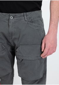 Pantalones cargo grises con un ajuste slim, fabricados con un tejido duradero. Presentan múltiples bolsillos y una cinturilla con botones para un cierre seguro.