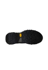 Black rubber shoe sole featuring a jagged tread pattern with a yellow accent, designed for traction and durability, with a sturdy build.