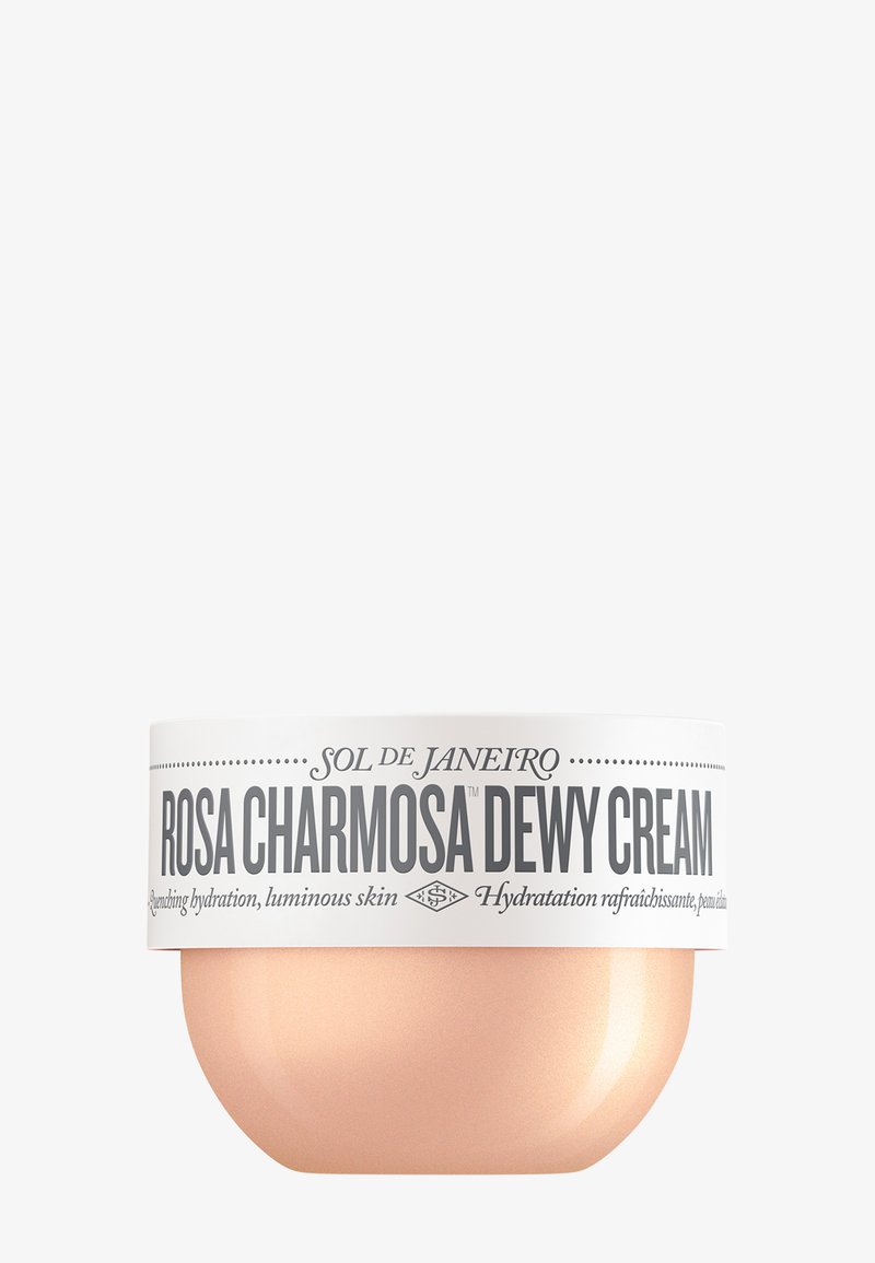 Rosa Charmosa Dewy Crème in een ronde, roségouden verpakking met een wit etiket met zwarte tekst. Romige textuur met een glanzende afwerking.