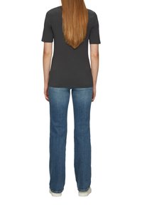 Donkergrijze, korte mouwen t-shirt met een ronde hals, gecombineerd met blauwe, uitlopende jeans en witte schoenen, van achteren weergegeven.