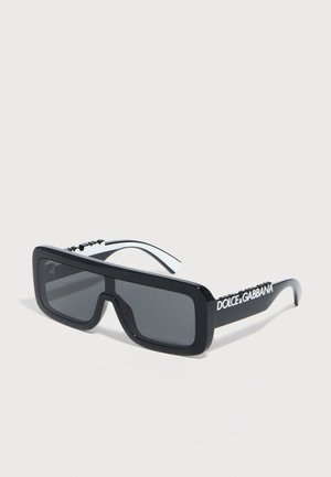 Occhiali da sole rettangolari neri con lenti scure, montatura spessa e logo "Dolce & Gabbana" sulle aste.