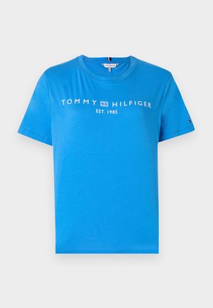 T-shirt de algodão azul com decote redondo e mangas curtas. A parte da frente tem o texto "TOMMY HILFIGER EST. 1985" em branco. Ajuste padrão.