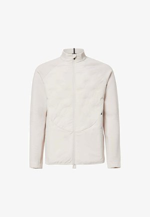 Helle beige Zip-Jacke mit gesteppter Vorderseite, hohem Kragen und geripptem Textil an Ärmeln und Seiten.