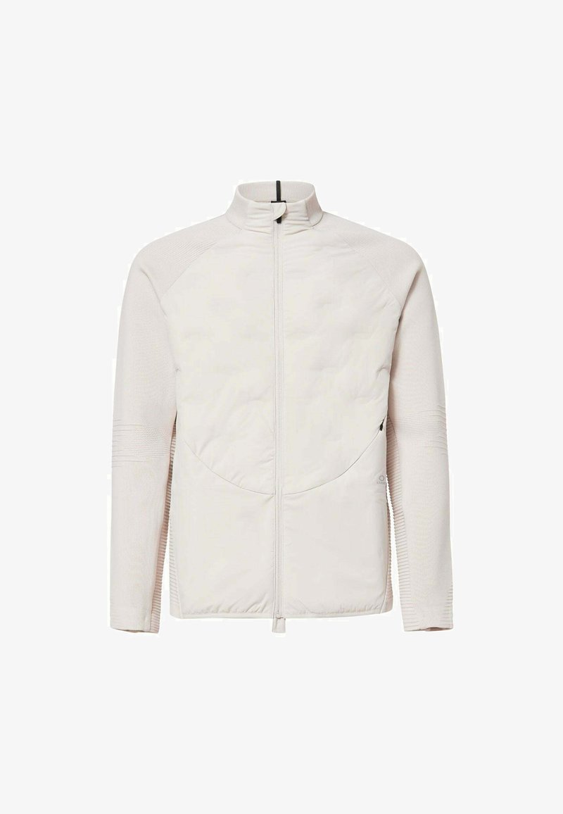 Helle beige Zip-Jacke mit gesteppter Vorderseite, hohem Kragen und geripptem Textil an Ärmeln und Seiten.