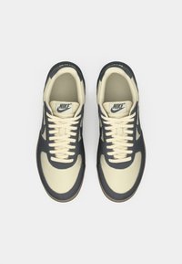 Sneakers Nike in crema e blu navy. Materiale in tela e pelle, punta rotonda, con lacci, colletto imbottito, suola in gomma e marchio sulla linguetta.