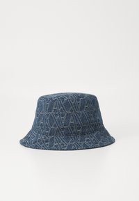 Denim cepure ar zilu bāzi. Tam ir rakstura tekstūra ar logo detaļām un plašu, slīpumu malu.