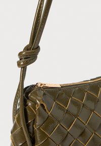 Olivgrüne, geflochtene Lederhandtasche mit glanzvollem Finish, ausgestattet mit einem Reißverschluss und miteinander verflochtenen Lederträgern. Goldene Hardware-Akzente inklusive.
