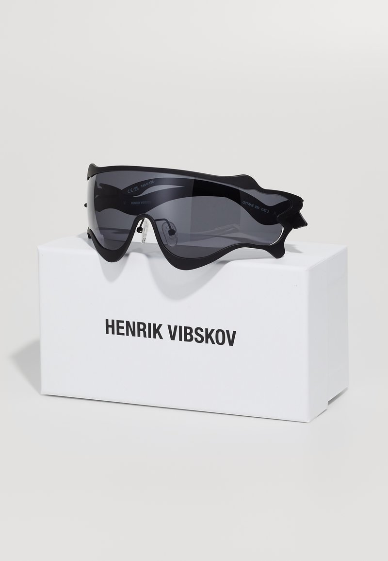 Black oversized sunglasses with a sleek design and tinted lenses, displayed on a white box labeled "HENRIK VIBSKOV."