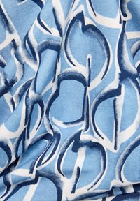 Blauer Stoff mit einem wirbelnden Kreisdesign in Weiß und Marineblau. Die Textur ist glatt mit einem leichten Glanz, was auf ein leichtes Material hinweist.