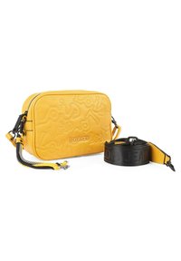 Bolso cruzado texturizado amarillo con lettering en relieve. Presenta una correa negra desmontable con logotipo y tiradores de cremallera en contraste.