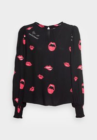 Svart långärmad blus med smockade manschetter, prydd med röda läpptryck och frasen "livet är fantastiskt" på den övre vänstra axeln.