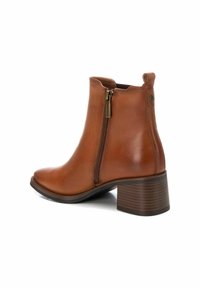 Bottino in pelle marrone con punta rotonda, cerniera laterale e tacco impilato. Presenta una texture liscia e un design minimalista.