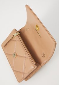 Small beige leather purse with gold zipper, magnetic snap closure, and quilted stitching, shown open against white background.