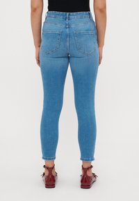 Magas derékú, világoskék skinny farmernadrág, ami denim anyagból készült. Jellemzői a két hátsó zseb és a lábak mentén vékony illeszkedés, felgörgő szegélyek.