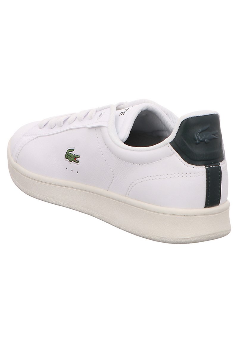 Białe skórzane sneakersy z zielonym akcentem na pięcie, okrągłym noskiem, płaską podeszwą oraz małym haftowanym logo krokodyla po boku.