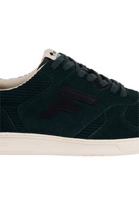 Sneaker in suede verde scuro con logo "F" nero, lacci neri, interno beige e suola avorio su sfondo bianco.