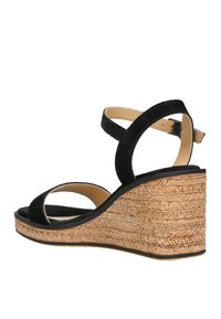 Sandalo con zeppa in suede nero, dal design aperto, con cinturini larghi e una suola intermedia in juta intrecciata. Presenta un cinturino posteriore con fibbia regolabile.