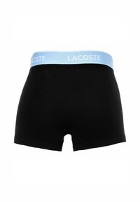 Boxer in cotone nero con elastico azzurro chiaro che presenta la scritta "LACOSTE" in bianco. Design semplice con una texture liscia.