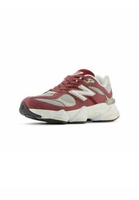 Zapatilla roja y gris que presenta materiales de malla, ante y goma, con una suela acolchada y acentos texturizados en la parte superior y los cordones.