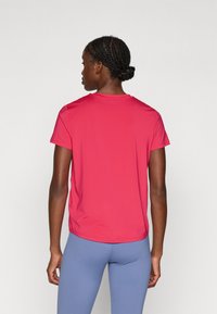 Camiseta deportiva de manga corta y cuello redondo en un sólido color rosa brillante, hecha de tejido ligero, con un corte relajado y una textura suave.