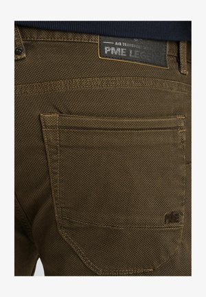 Braune Stoffhosen mit strukturiertem Gewebe, ausgestattet mit einer Gesäßtasche und einem schwarzen Etikett mit "PME Legend" Branding, akzentuiert mit gelben Nähten.