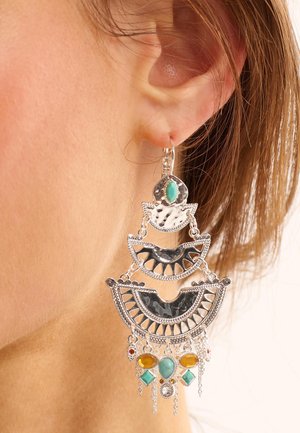 Boucles d'oreilles en argent pendantes avec des motifs géométriques complexes, ornées d'accents en turquoise et ambre, de filigrane détaillé et de chaînes pendantes.