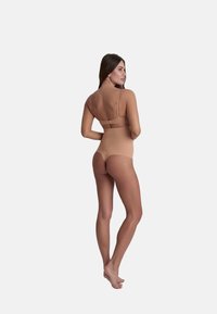 Beige bodysuit met een naadloos ontwerp, verstelbare bandjes en een hoge taille, met een gladde textuur en minimale details.