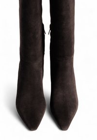 Melnas zamšādas potītes zābaki ar smailu purngalu un pieguļošu dizainu. Aprīkoti ar sānu rāvējslēdzējiem ērtai uzvilkšanai. Gluda teksturēta virsma.