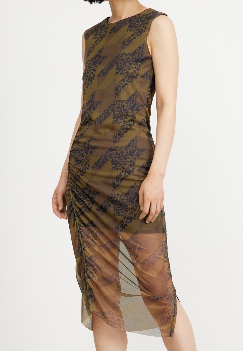 Vestido sin mangas en tela marrón transparente con un patrón geométrico y acentos florales oscuros. Presenta detalles fruncidos en los laterales y un corte a la altura de la rodilla.